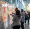 a vibrant and dynamic brainstorming session unfolds in a modern office, showcasing diverse team members collaboratively planning and strategizing digital content on a sleek whiteboard filled with colorful sticky notes and diagrams, illuminated by natural light streaming through large windows.
