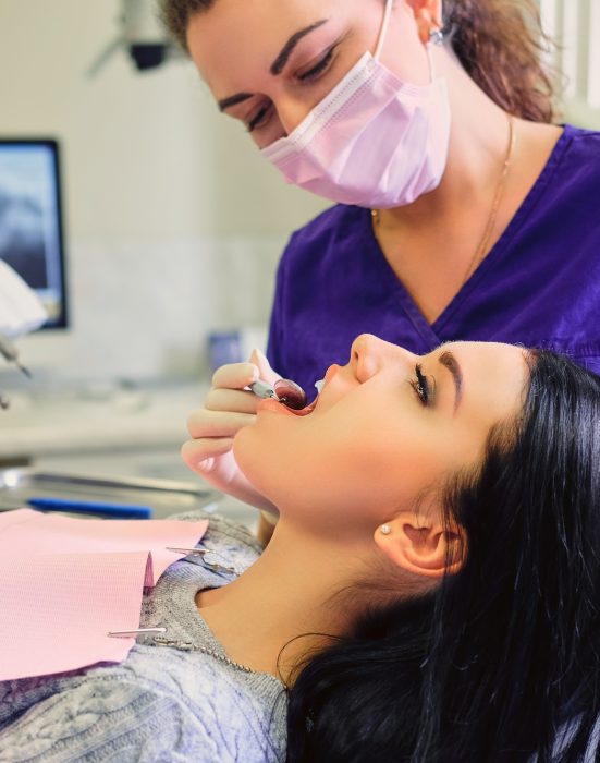 Dentist examining female's teeth in dentistry.