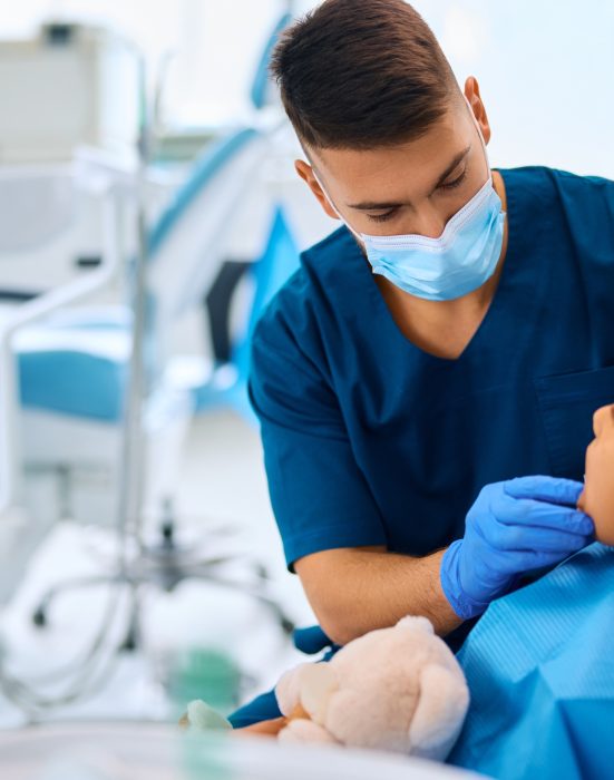 Dentist examining teeth of little black girl at dental clinic.